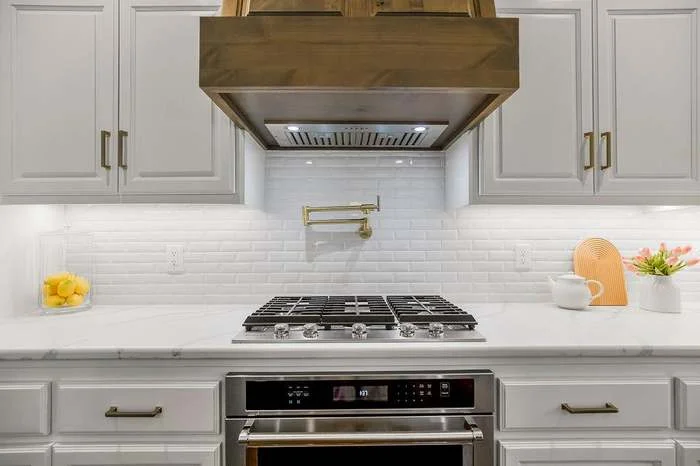 Modern kitchen featuring gas cooktop, white subway backsplash, and wood range hood by Stag Homes Design-Build in Kansas City
