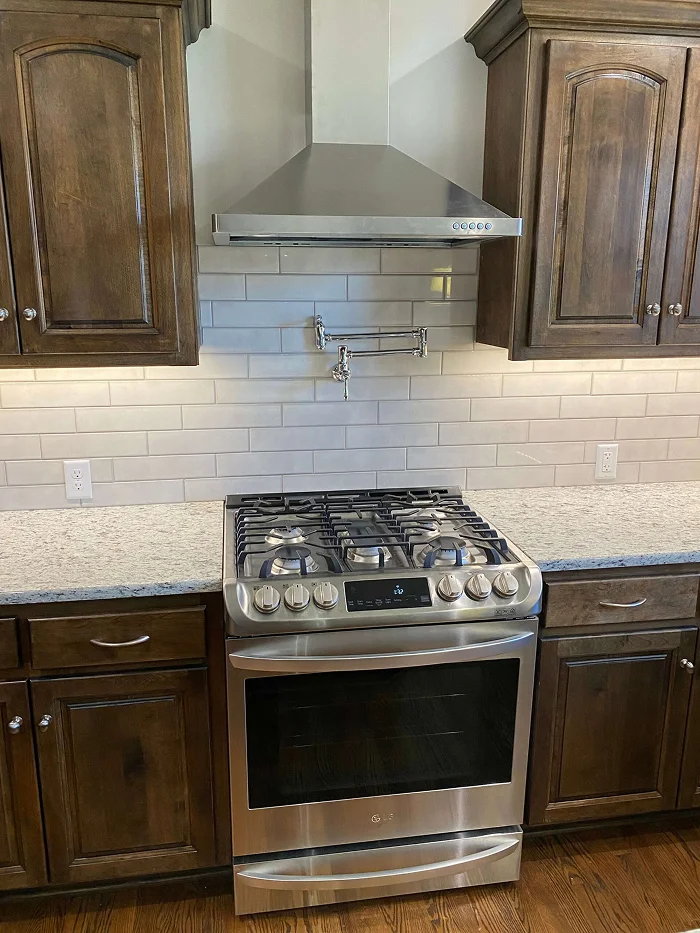 Modern gas range with dark wood cabinets and stainless steel hood by Stag Homes Design-Build in Kansas City