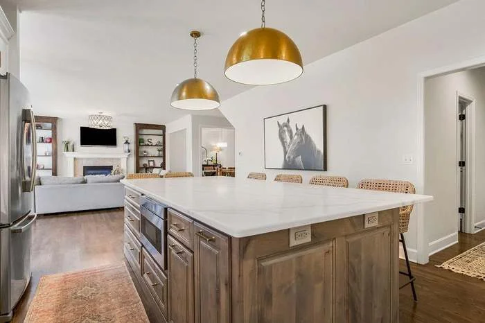 Open-concept kitchen with large island, gold pendant lights, and wood cabinetry by Stag Homes Design-Build in Kansas City